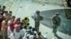 US soldiers stand guard as Afghan people wait at the Kabul airport in Kabul on August 16, 2021, after a stunningly swift end to Afghanistan's 20-year war, as thousands of people mobbed the city's airport trying to flee the group's feared hardline brand…