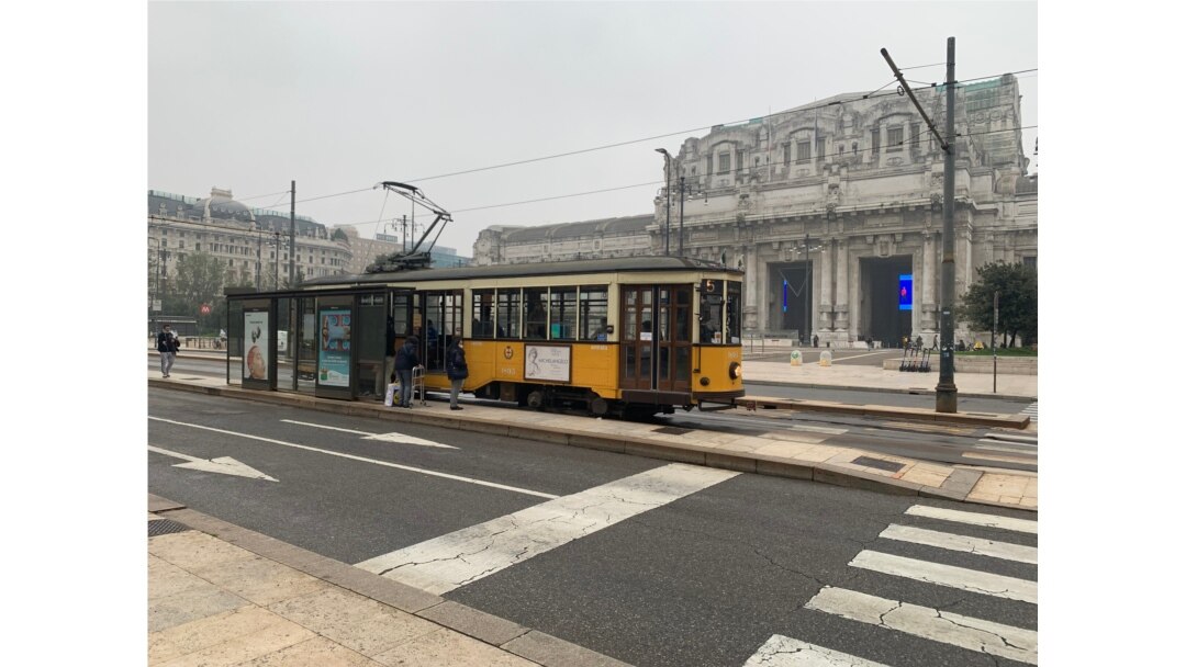 An empty Milan central railway station is seen with an almost empty traditional tram in front of it. (Sabina Castelfranco/VOA)