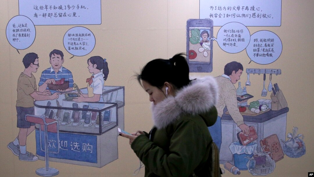 2019年1月3日在北京一個地鐵站，女子看著手機，走過推廣iPhone的壁畫。
